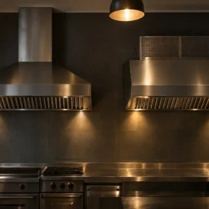 Hotte professionnelle en inox au-dessus d’une plaque de cuisson dans une cuisine industrielle.